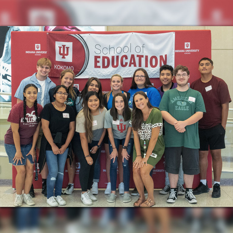 Members of the Tomorrow's Teachers program gather for a photograph underneath a banner advertising for the Indiana University School of Education