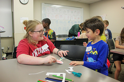 IU School of Education undergraduate student Amelia Dickson helps an elementary student make a paper representation of a total solar eclipse. 